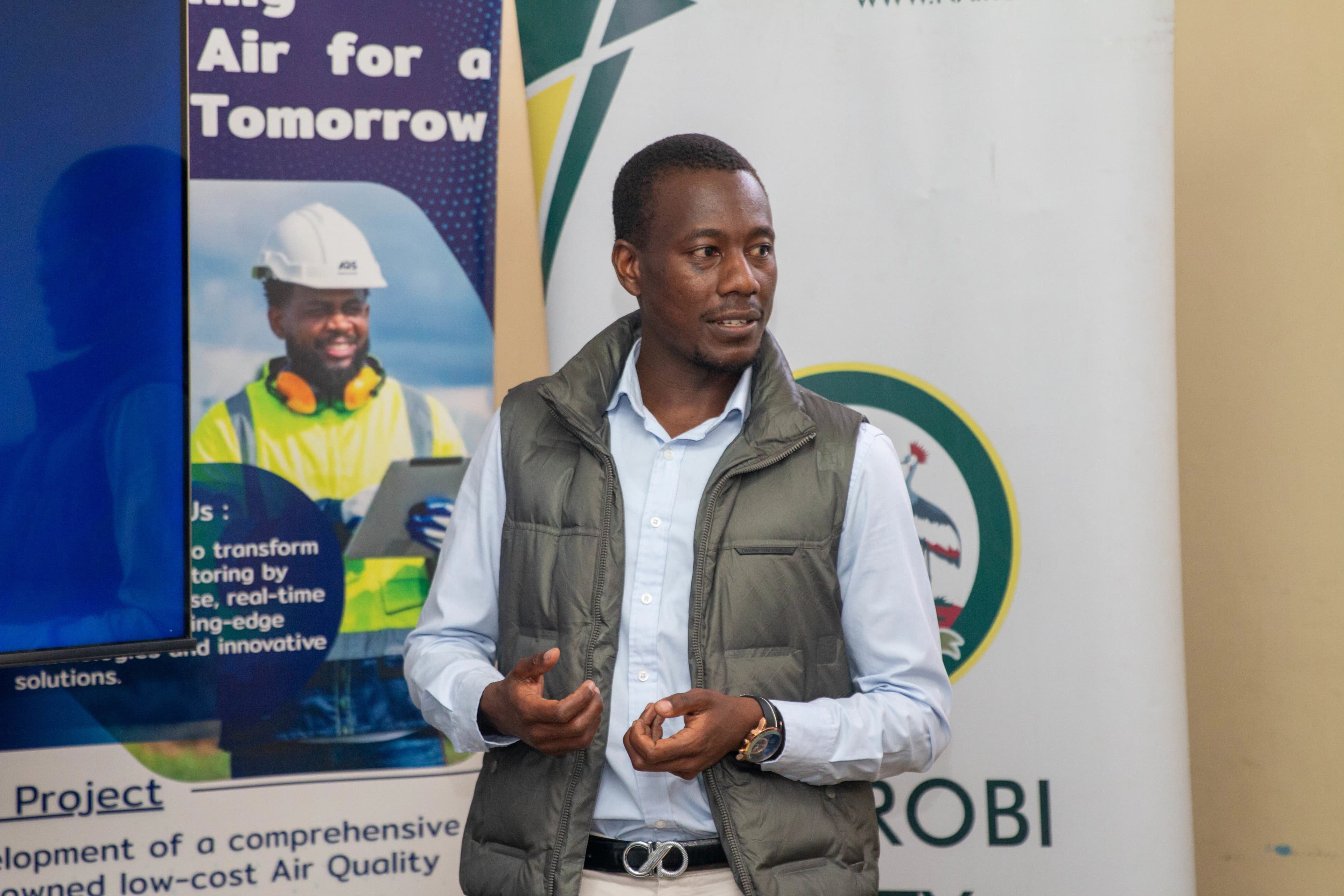 Muran Systems field director wearing a white hard hat, pointing at an air quality sensor mounted on a pole during a training session in Nairobi County